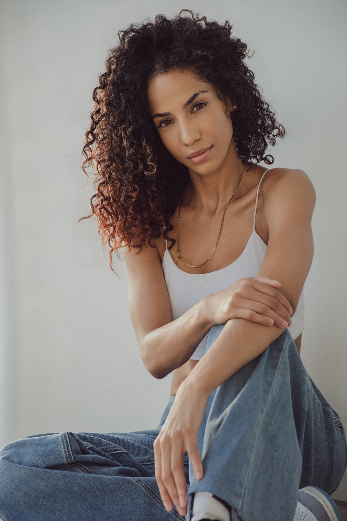 Christal seated with arms resting on her knee, looking into the camera