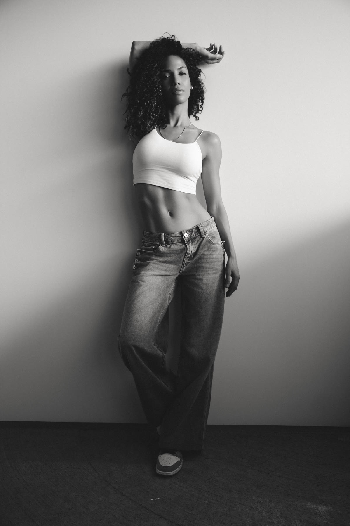 Black and white full length portrait of Christal against a studio wall
